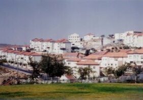 View of a hillside town with red-roofed buildings and greenery.