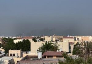 Hazy city skyline with buildings and trees under a gray sky.