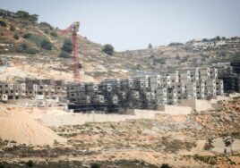 Buildings under construction on a rocky hillside with a crane nearby.
